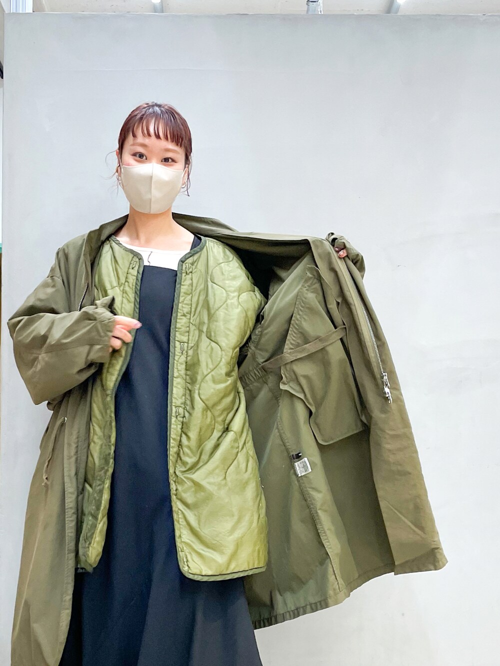 グリーン系のミリタリージャケット、ブラック系のワンピース/ドレス、ブラック系のブーツを着用したレディースの冬コーディネートの2枚目の写真