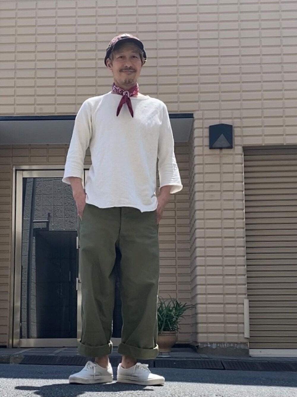 ホワイト系のTシャツ/カットソー、グリーン系のパンツ、ホワイト系のスニーカーを着用したメンズの春コーディネートの2枚目の写真