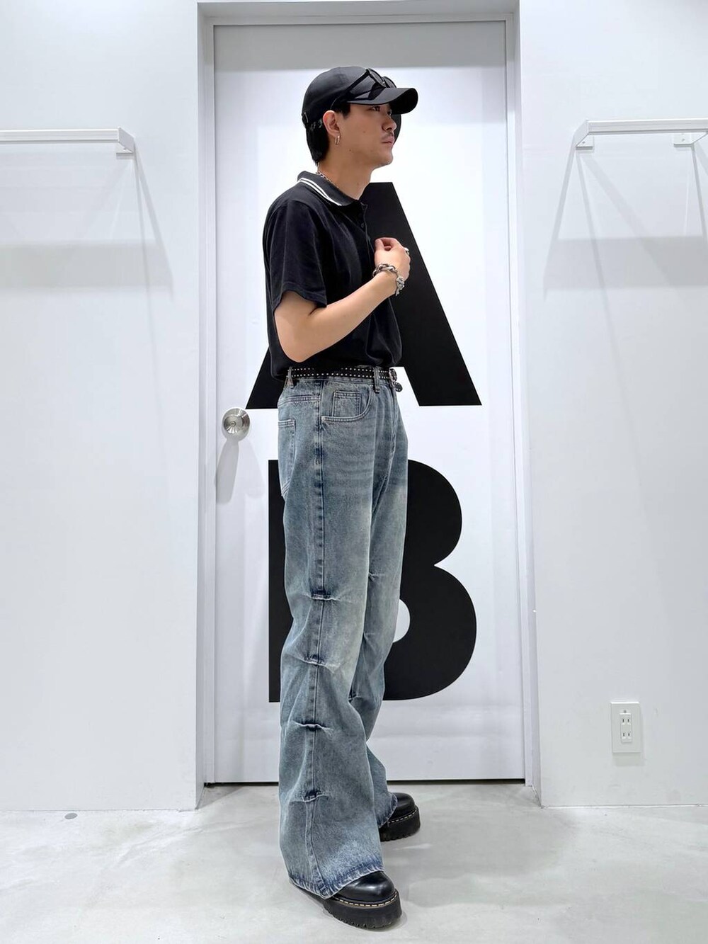 ブラック系のポロシャツ、グレー系のデニムパンツ、ブラック系のサングラスを着用したメンズの夏コーディネートの3枚目の写真