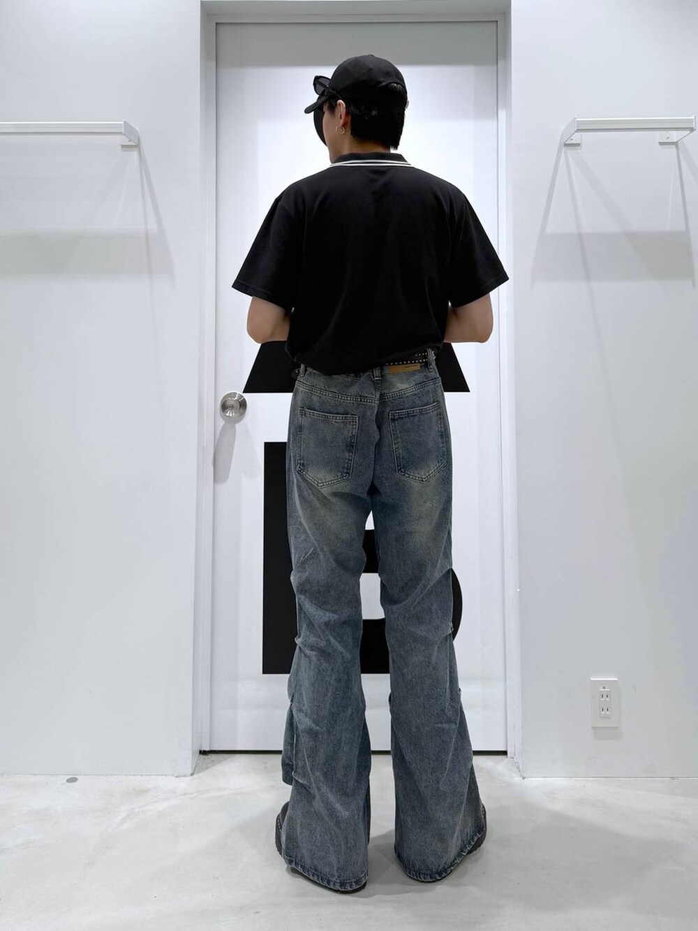 ブラック系のポロシャツ、グレー系のデニムパンツ、ブラック系のサングラスを着用したメンズの夏コーディネートの5枚目の写真
