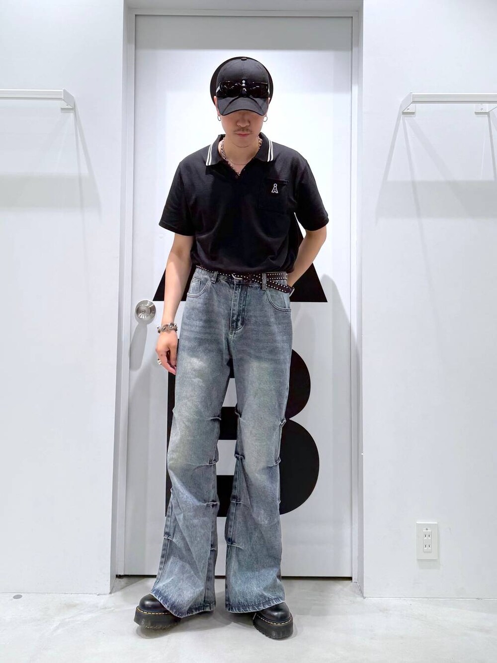 ブラック系のポロシャツ、グレー系のデニムパンツ、ブラック系のサングラスを着用したメンズの夏コーディネートの2枚目の写真