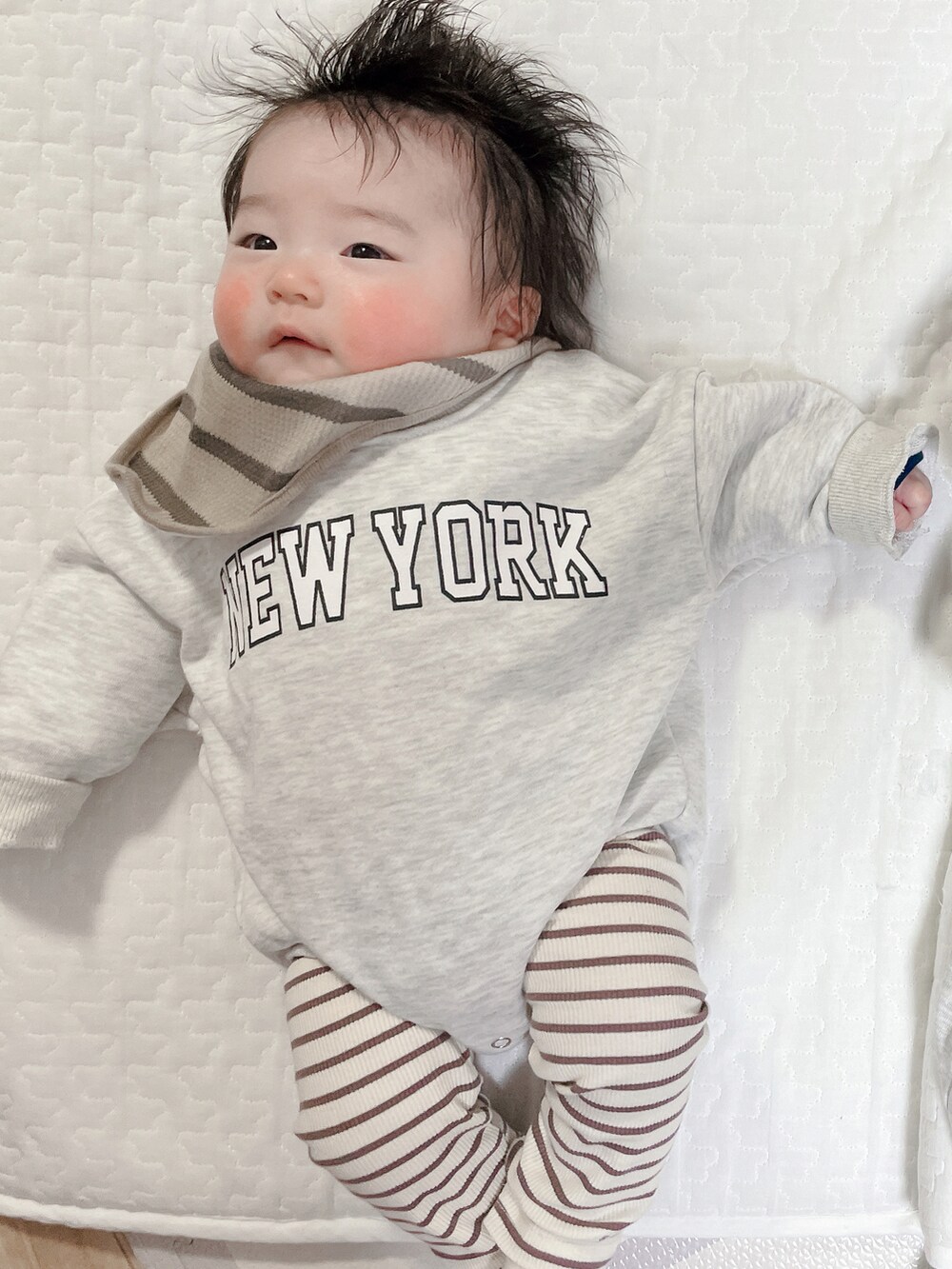 グレー系のロンパース、ベージュ系のその他ベビーウェア、ブラウン系のスタイ/よだれかけを着用したキッズの春コーディネートの2枚目の写真