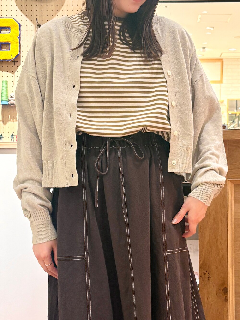 ベージュ系のカーディガン/ボレロ、ブラウン系のスカート、イエロー系のTシャツ/カットソーを着用したレディースの夏コーディネートの5枚目の写真