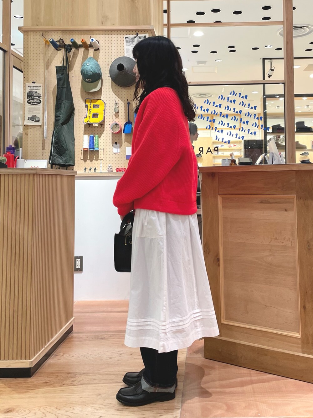 オレンジ系のカーディガン/ボレロ、ブルー系のTシャツ/カットソー、ホワイト系のスカートを着用したレディースの秋コーディネートの2枚目の写真