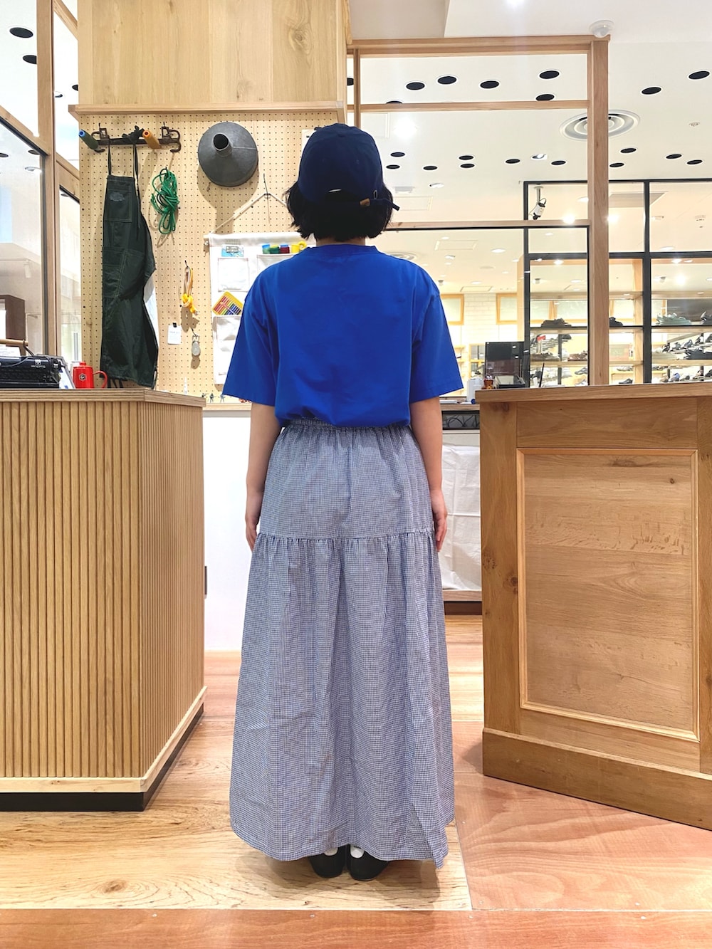 ブルー系のスカート、ブルー系のTシャツ/カットソー、ブルー系のキャップを着用したレディースの夏コーディネートの3枚目の写真