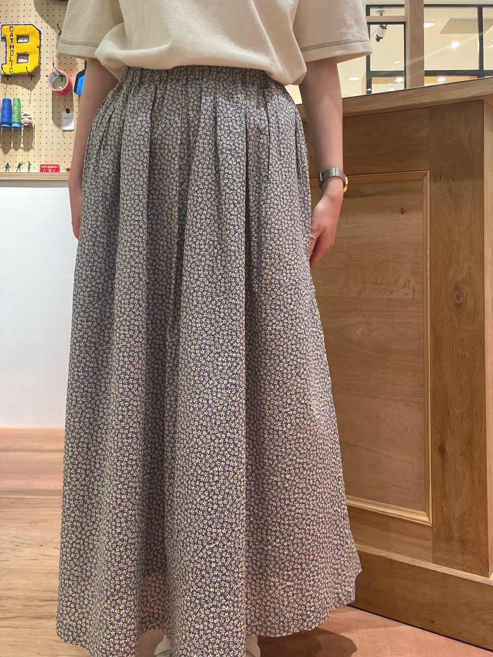 イエロー系のスカート、ブラウン系のショルダーバッグ、ホワイト系のポロシャツを着用したレディースの春コーディネートの4枚目の写真