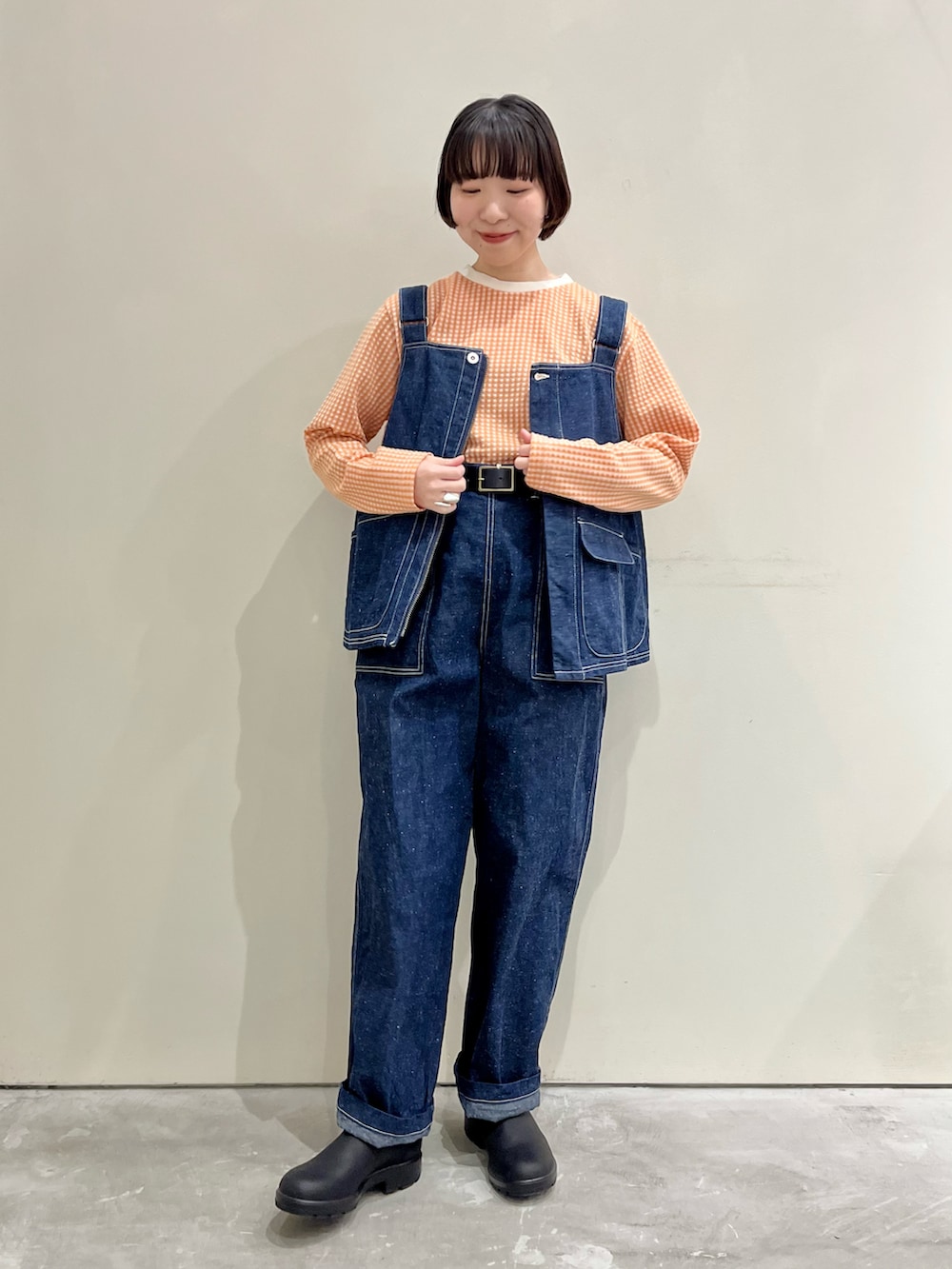 オレンジ系のTシャツ/カットソー、ブルー系のベスト、ブルー系のその他パンツを着用したレディースの冬コーディネートの2枚目の写真