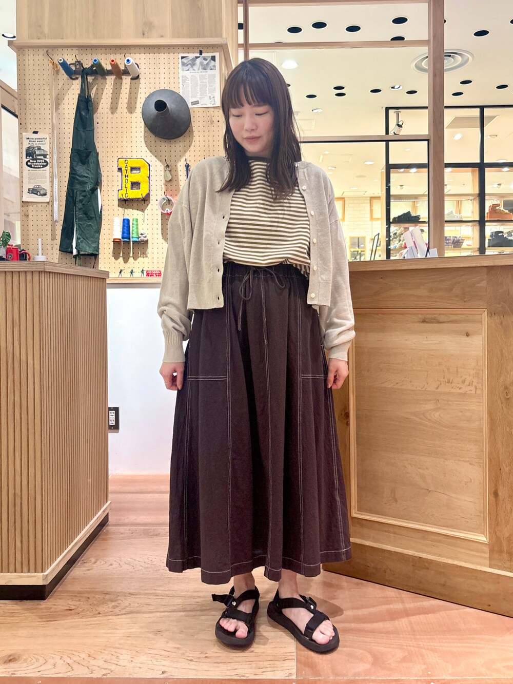 ベージュ系のカーディガン/ボレロ、ブラウン系のスカート、イエロー系のTシャツ/カットソーを着用したレディースの夏コーディネートの4枚目の写真