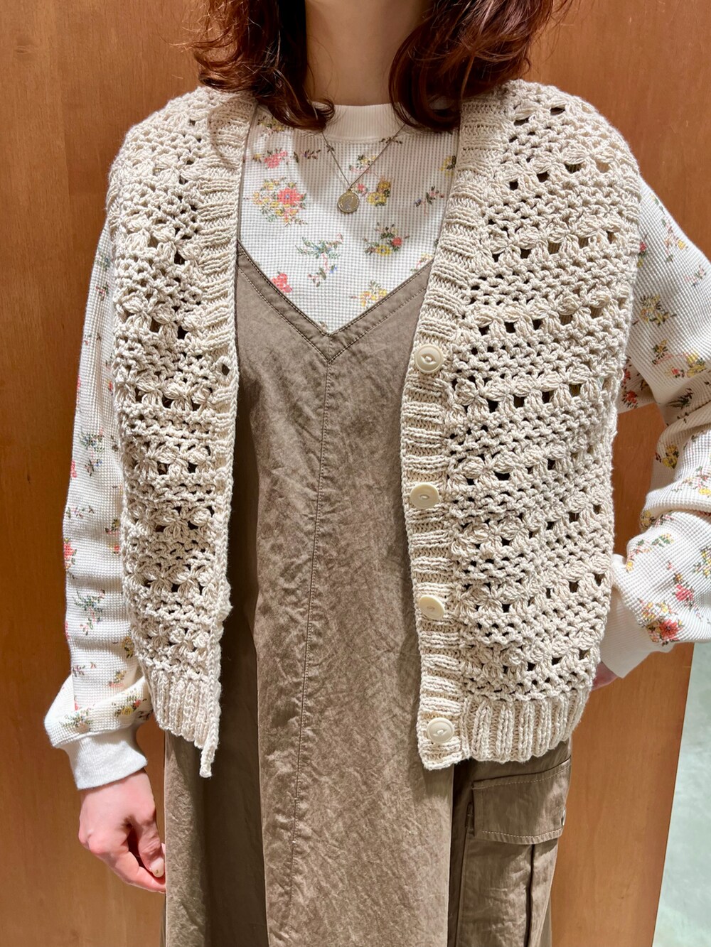 ホワイト系のベスト、オレンジ系のTシャツ/カットソー、ベージュ系のジャンパースカートを着用したレディースの冬コーディネートの3枚目の写真