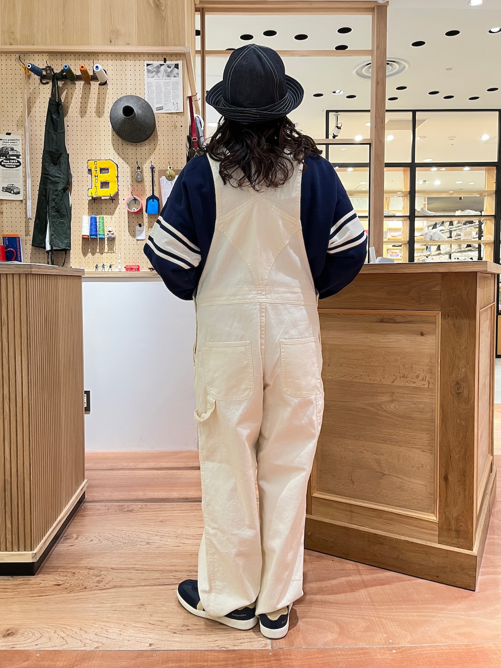 ブルー系のスウェット、ホワイト系のサロペット/オーバーオール、ブルー系のハットを着用したレディースの冬コーディネートの3枚目の写真