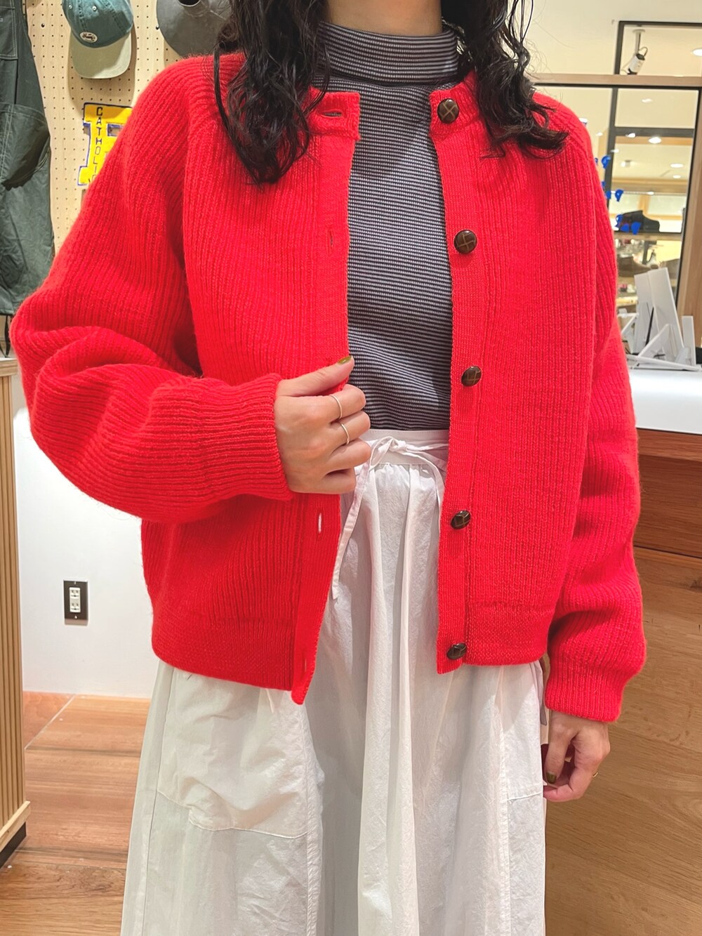 オレンジ系のカーディガン/ボレロ、ブルー系のTシャツ/カットソー、ホワイト系のスカートを着用したレディースの秋コーディネートの7枚目の写真