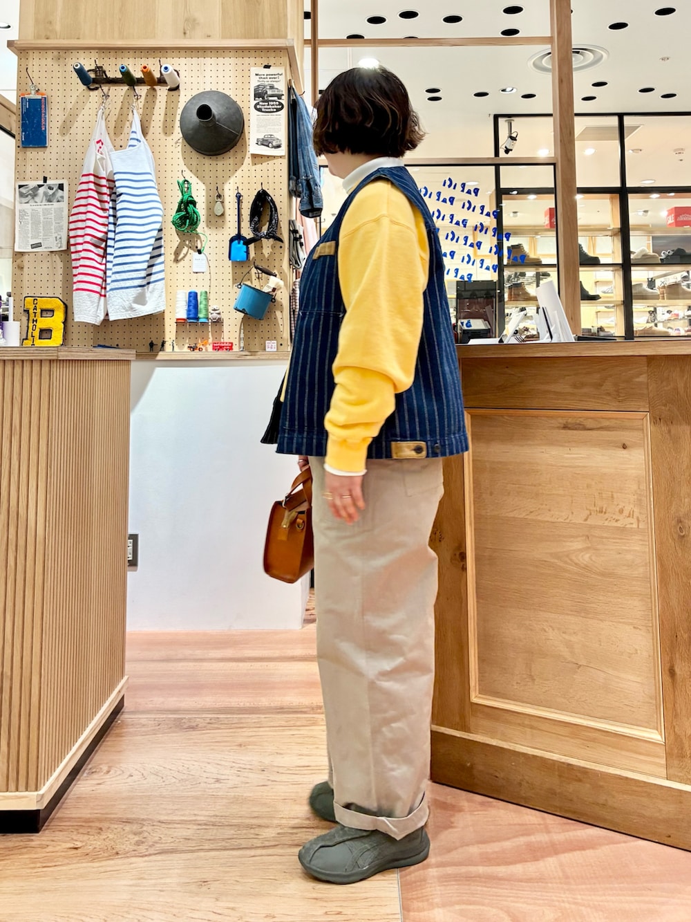 ホワイト系のTシャツ/カットソー、ブラウン系のショルダーバッグ、ベージュ系のチノパンツを着用したレディースの冬コーディネートの2枚目の写真