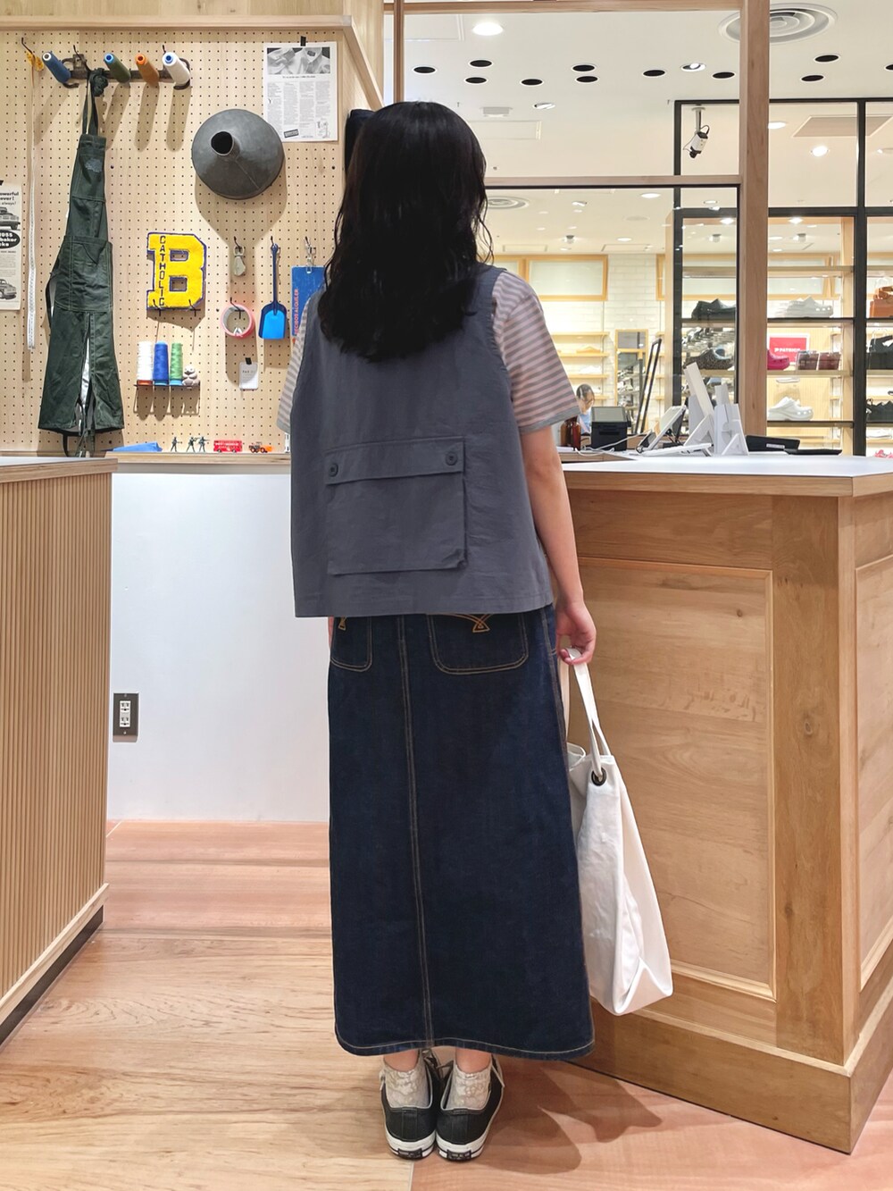 ブルー系のデニムスカート、ホワイト系のトートバッグ、ピンク系のTシャツ/カットソーを着用したレディースの夏コーディネートの2枚目の写真