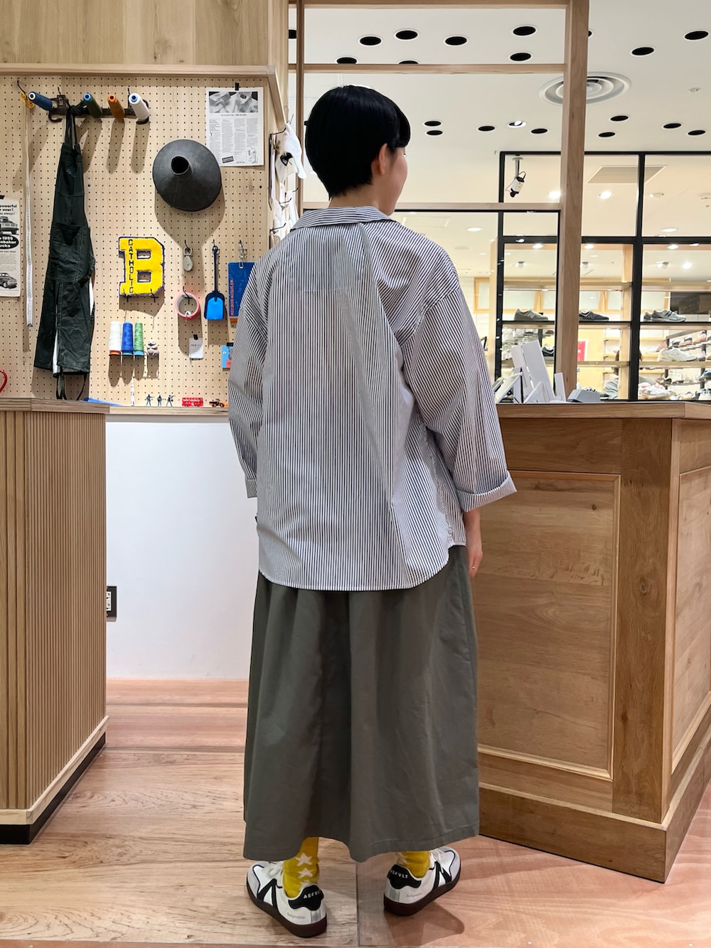 イエロー系のTシャツ/カットソー、ホワイト系のシャツ/ブラウス、グリーン系のスカートを着用したレディースの春コーディネートの3枚目の写真