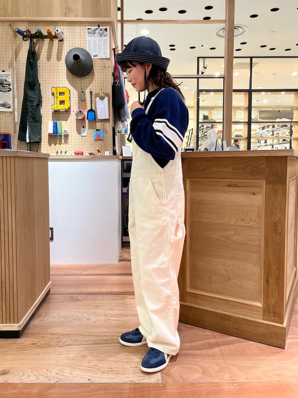 ブルー系のスウェット、ホワイト系のサロペット/オーバーオール、ブルー系のハットを着用したレディースの冬コーディネートの2枚目の写真