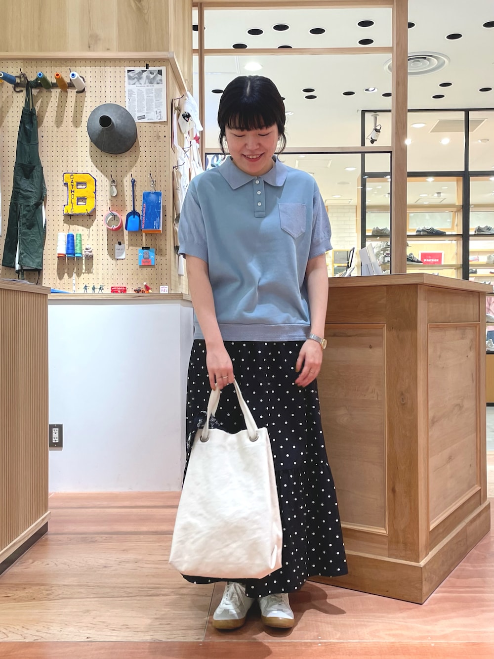 ブラック系のスカート、ブルー系のポロシャツ、ホワイト系のトートバッグを着用したレディースの春コーディネートの4枚目の写真