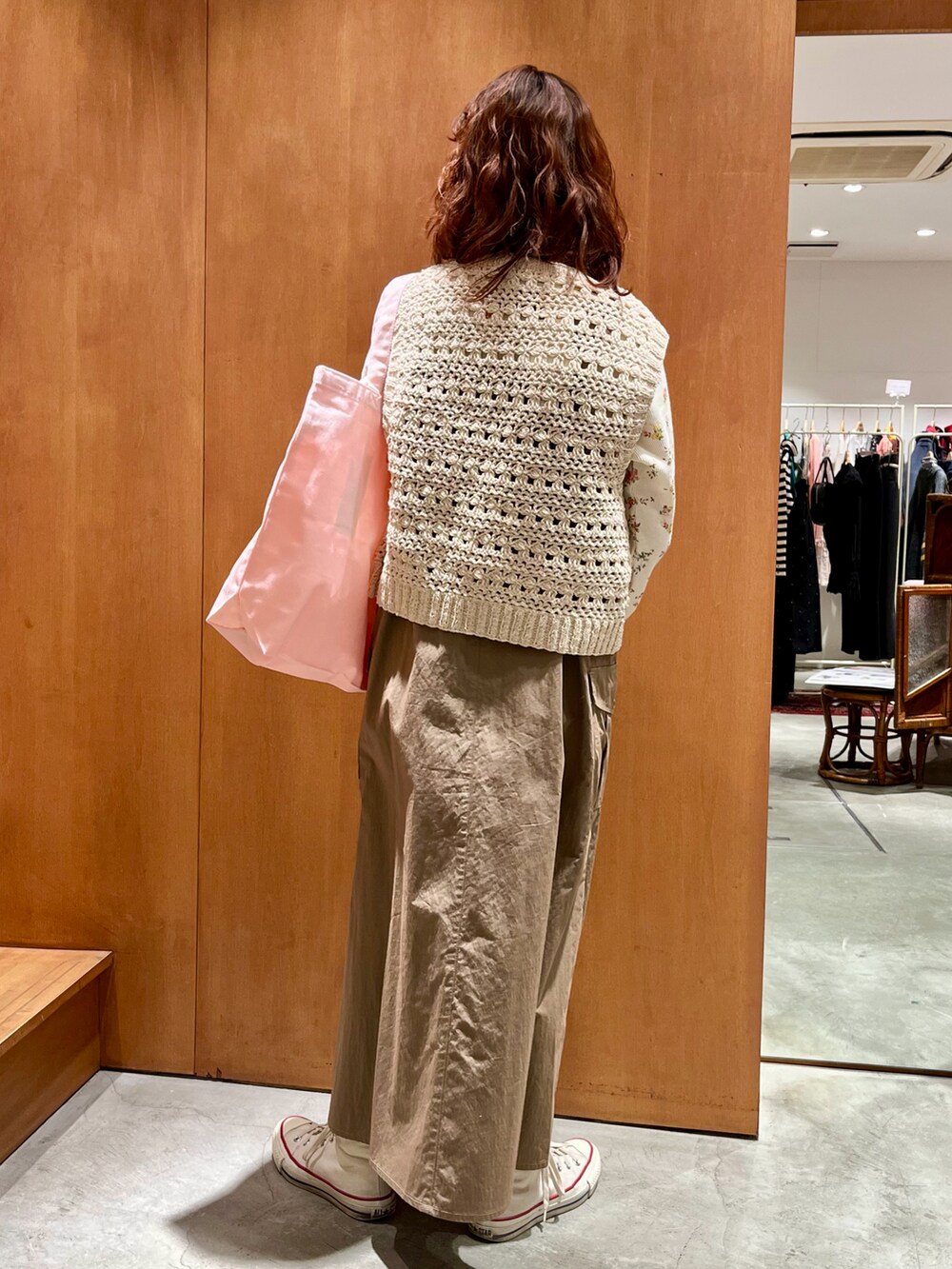 ホワイト系のベスト、オレンジ系のTシャツ/カットソー、ベージュ系のジャンパースカートを着用したレディースの冬コーディネートの2枚目の写真