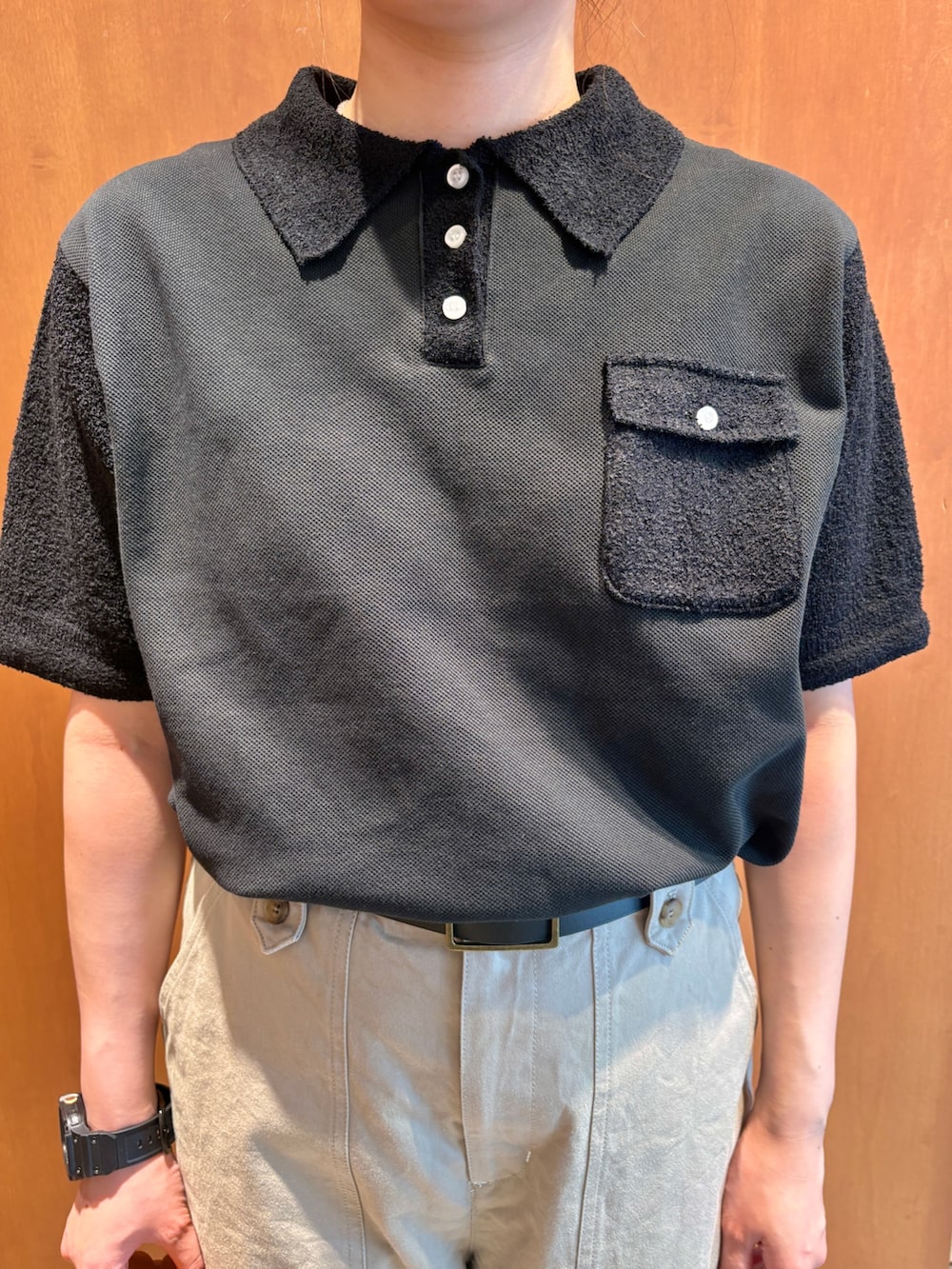 ブラック系のポロシャツ、ベージュ系のチノパンツ、ブラウン系のショルダーバッグを着用したレディースの夏コーディネートの4枚目の写真