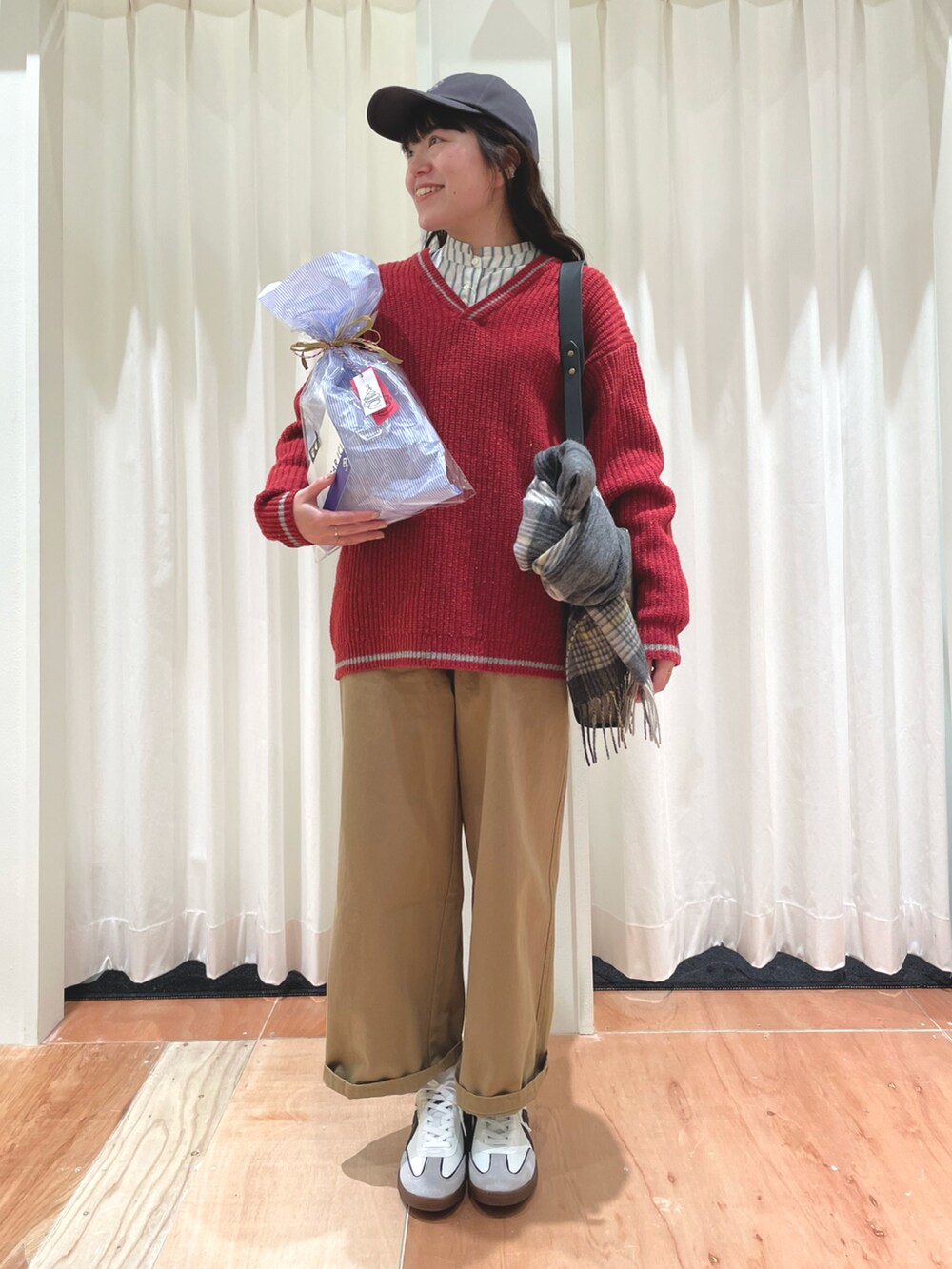 レッド系のニット/セーター、ベージュ系のチノパンツ、グリーン系のシャツ/ブラウスを着用したレディースの冬コーディネートの4枚目の写真