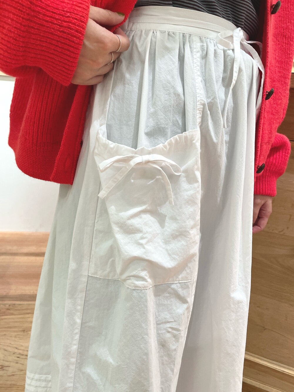 オレンジ系のカーディガン/ボレロ、ブルー系のTシャツ/カットソー、ホワイト系のスカートを着用したレディースの秋コーディネートの8枚目の写真