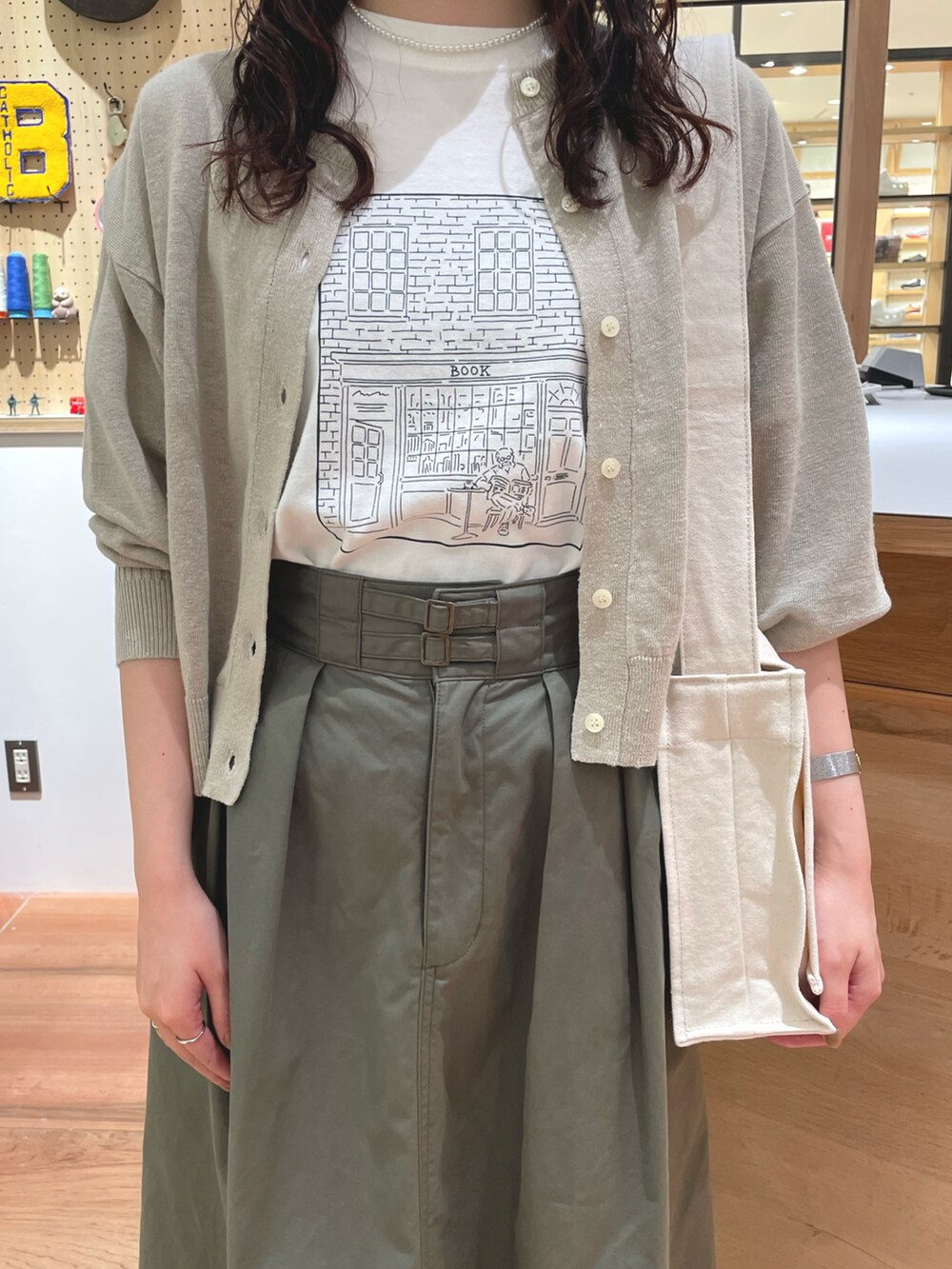 ホワイト系のTシャツ/カットソー、ベージュ系のカーディガン/ボレロ、ホワイト系のショルダーバッグを着用したレディースの春コーディネートの3枚目の写真