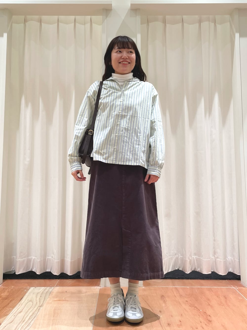 イエロー系のシャツ/ブラウス、グレー系のスカート、ホワイト系のTシャツ/カットソーを着用したレディースの冬コーディネートの2枚目の写真