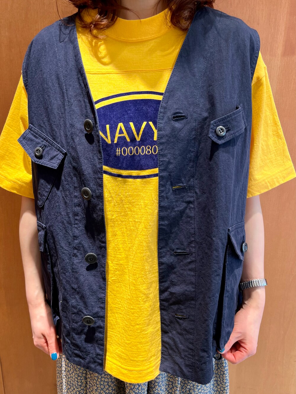 イエロー系のTシャツ/カットソー、ブルー系のベスト、イエロー系のスカートを着用したレディースの春コーディネートの3枚目の写真