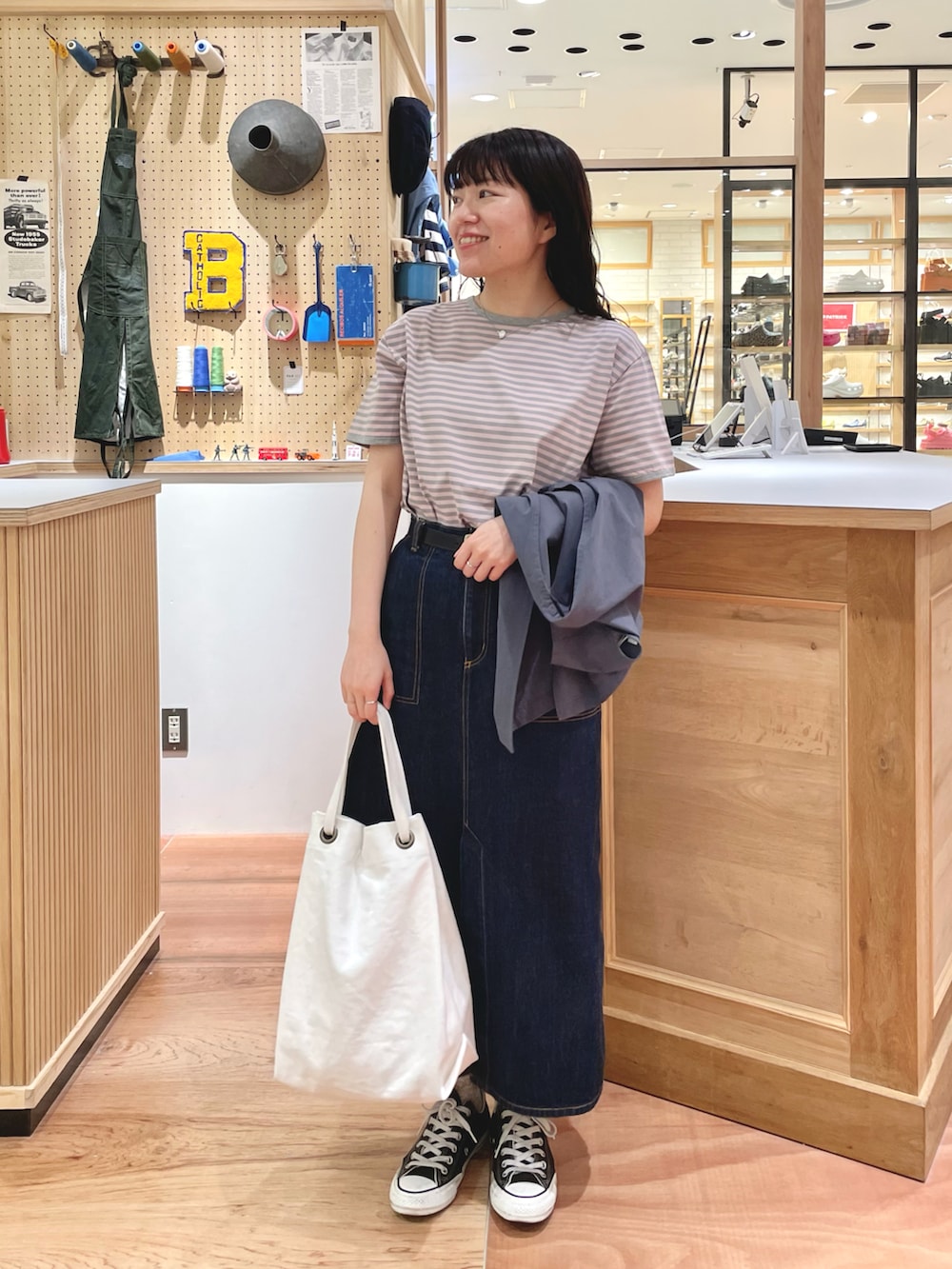 ブルー系のデニムスカート、ホワイト系のトートバッグ、ピンク系のTシャツ/カットソーを着用したレディースの夏コーディネートの4枚目の写真