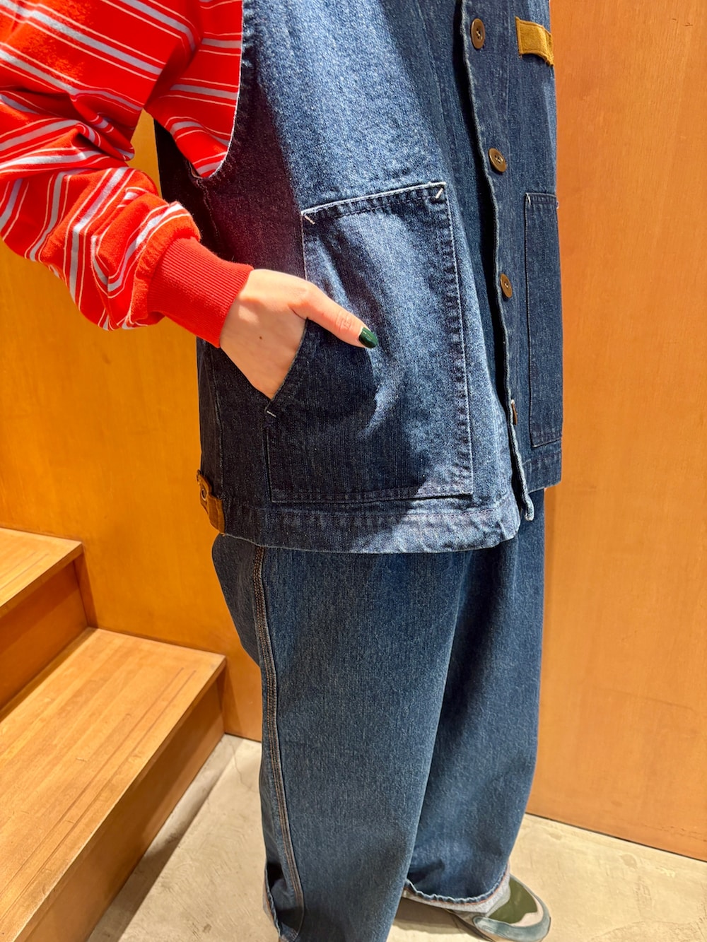 ブルー系のベスト、ブルー系のデニムパンツ、オレンジ系のTシャツ/カットソーを着用したレディースの春コーディネートの4枚目の写真