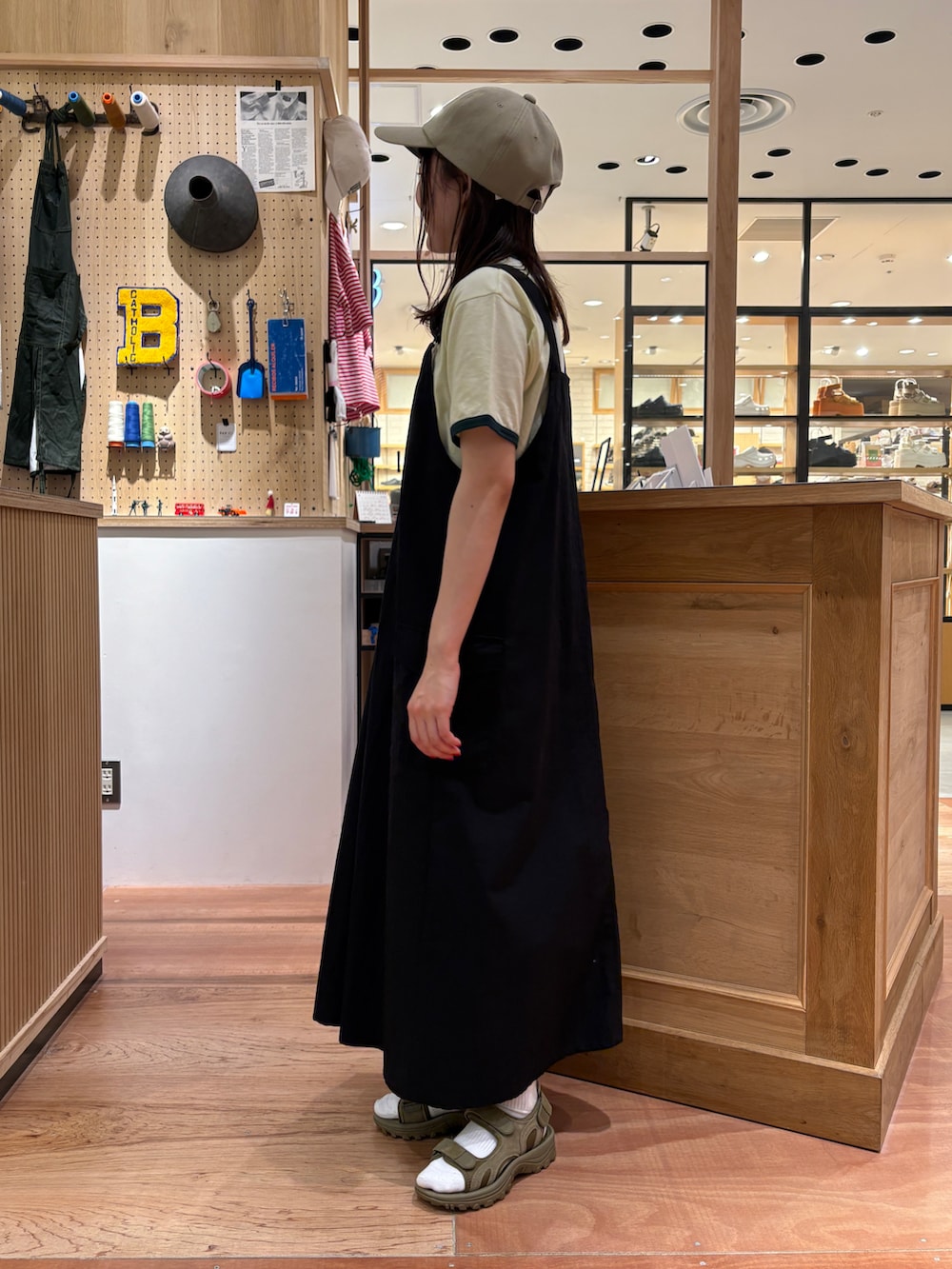 グリーン系のTシャツ/カットソー、ブラック系のジャンパースカート、グレー系のかごバッグを着用したレディースの春コーディネートの2枚目の写真