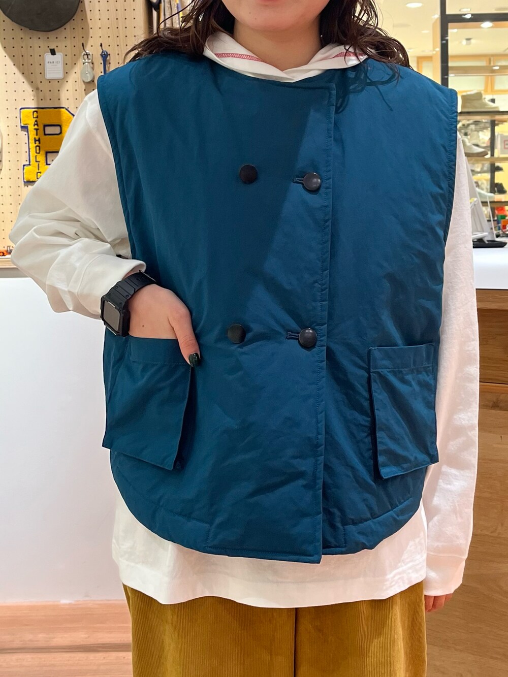 グリーン系のダウンベスト、イエロー系のその他パンツ、ホワイト系のTシャツ/カットソーを着用したレディースの秋コーディネートの4枚目の写真