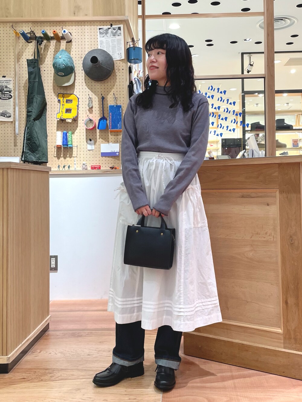 オレンジ系のカーディガン/ボレロ、ブルー系のTシャツ/カットソー、ホワイト系のスカートを着用したレディースの秋コーディネートの5枚目の写真