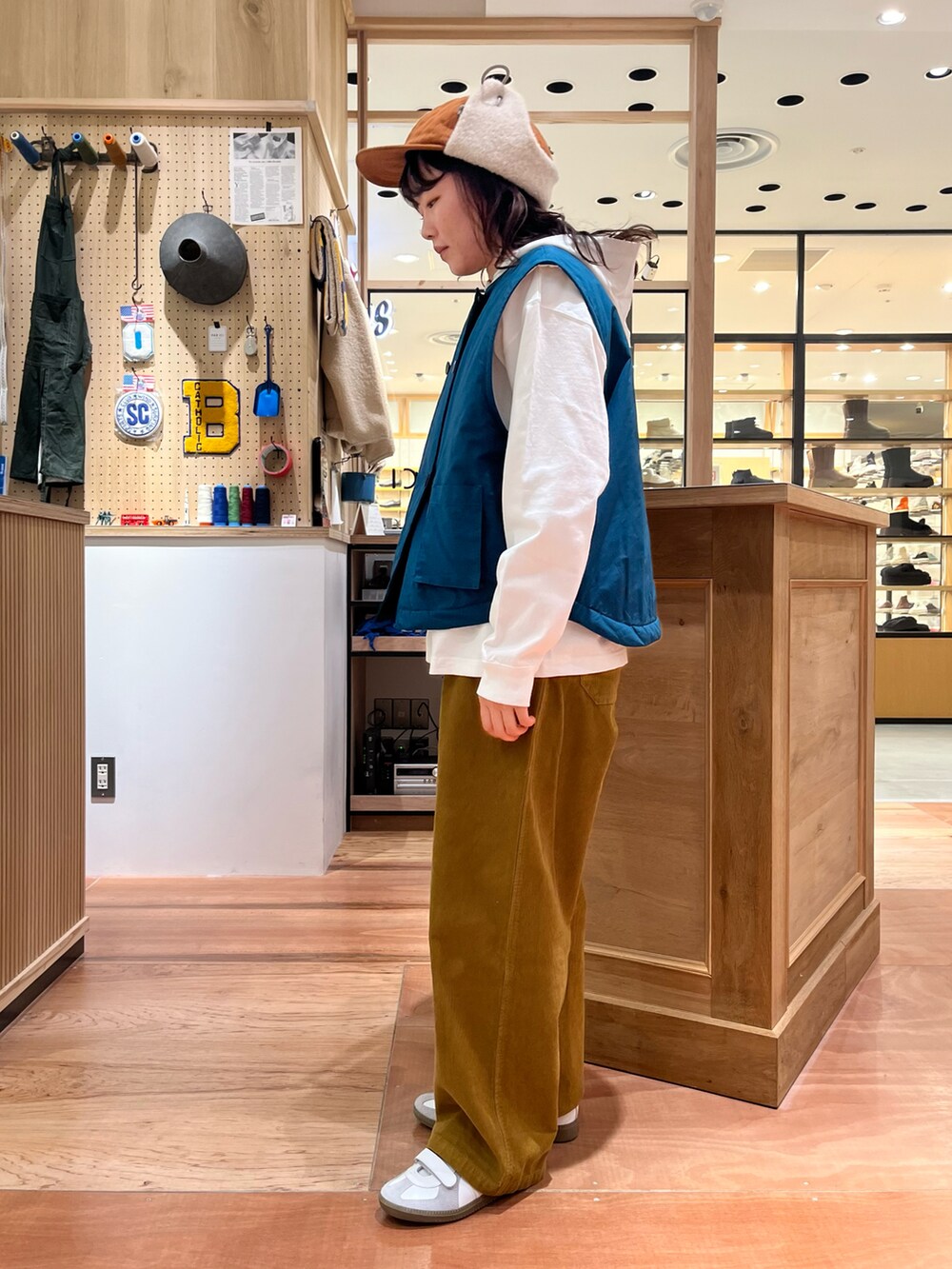 グリーン系のダウンベスト、イエロー系のその他パンツ、ホワイト系のTシャツ/カットソーを着用したレディースの秋コーディネートの2枚目の写真