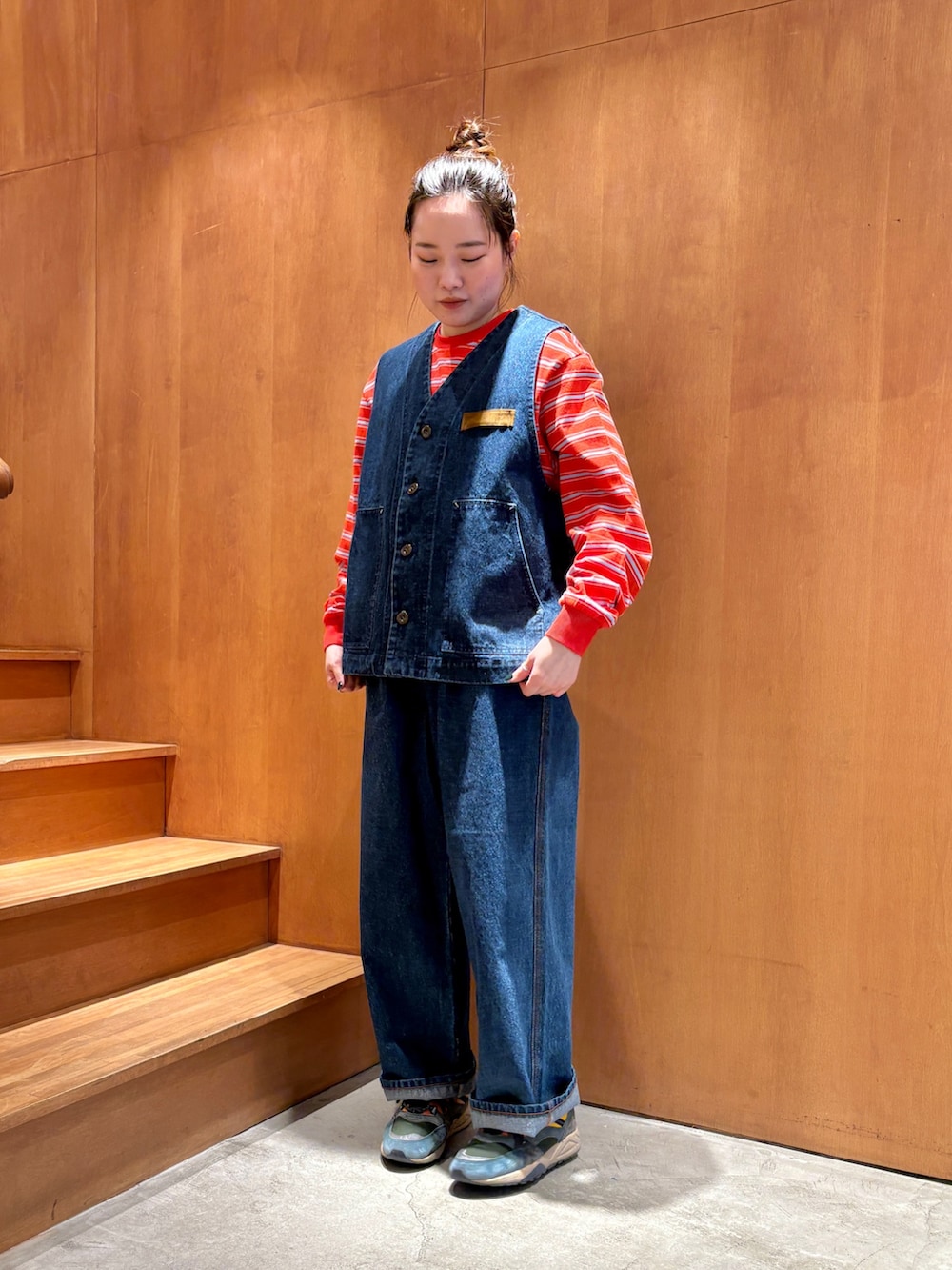 ブルー系のベスト、ブルー系のデニムパンツ、オレンジ系のTシャツ/カットソーを着用したレディースの春コーディネートの3枚目の写真