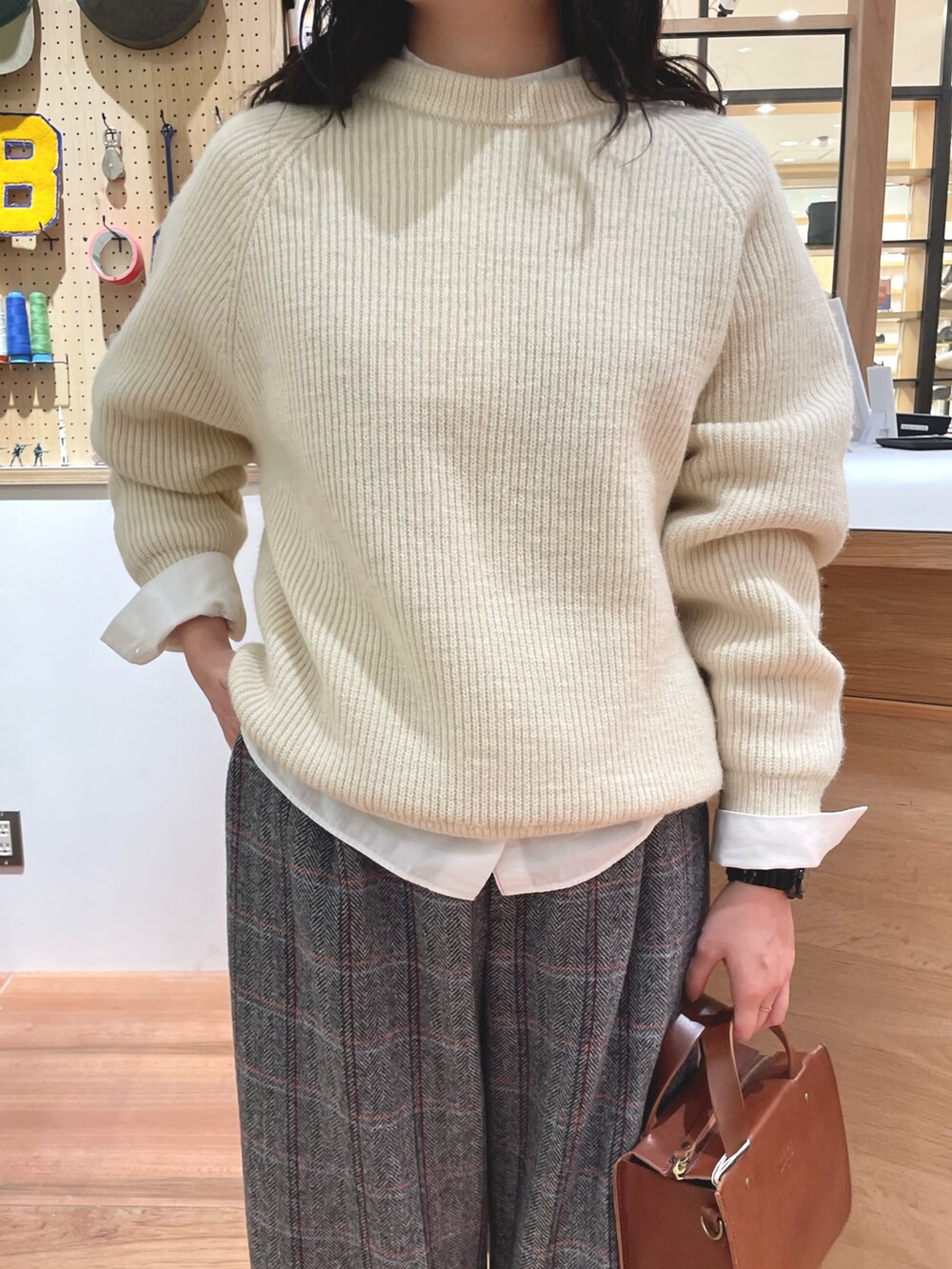 ホワイト系のシャツ/ブラウス、ホワイト系のニット/セーター、ブラウン系のショルダーバッグを着用したレディースの秋コーディネートの2枚目の写真