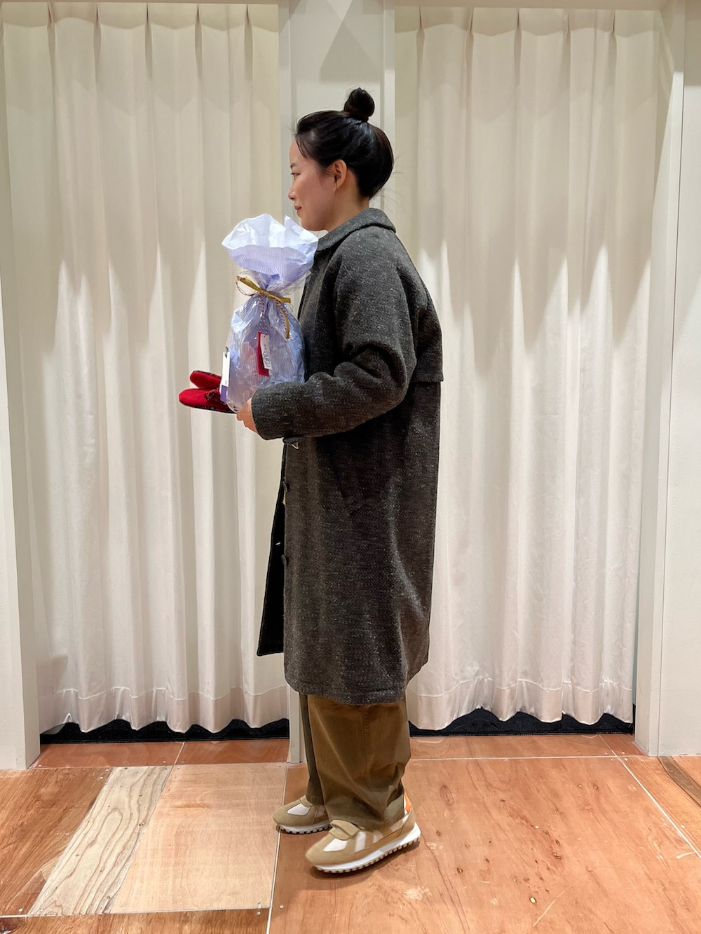 イエロー系のニット/セーター、ブラウン系のその他パンツ、グリーン系のステンカラーコートを着用したレディースの冬コーディネートの2枚目の写真