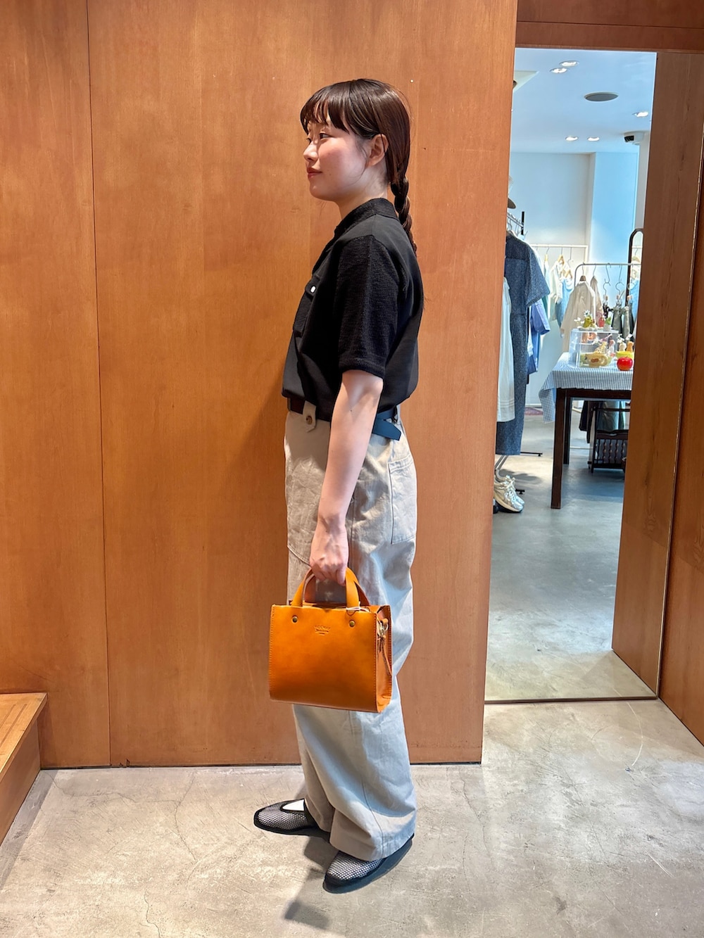 ブラック系のポロシャツ、ベージュ系のチノパンツ、ブラウン系のショルダーバッグを着用したレディースの夏コーディネートの2枚目の写真