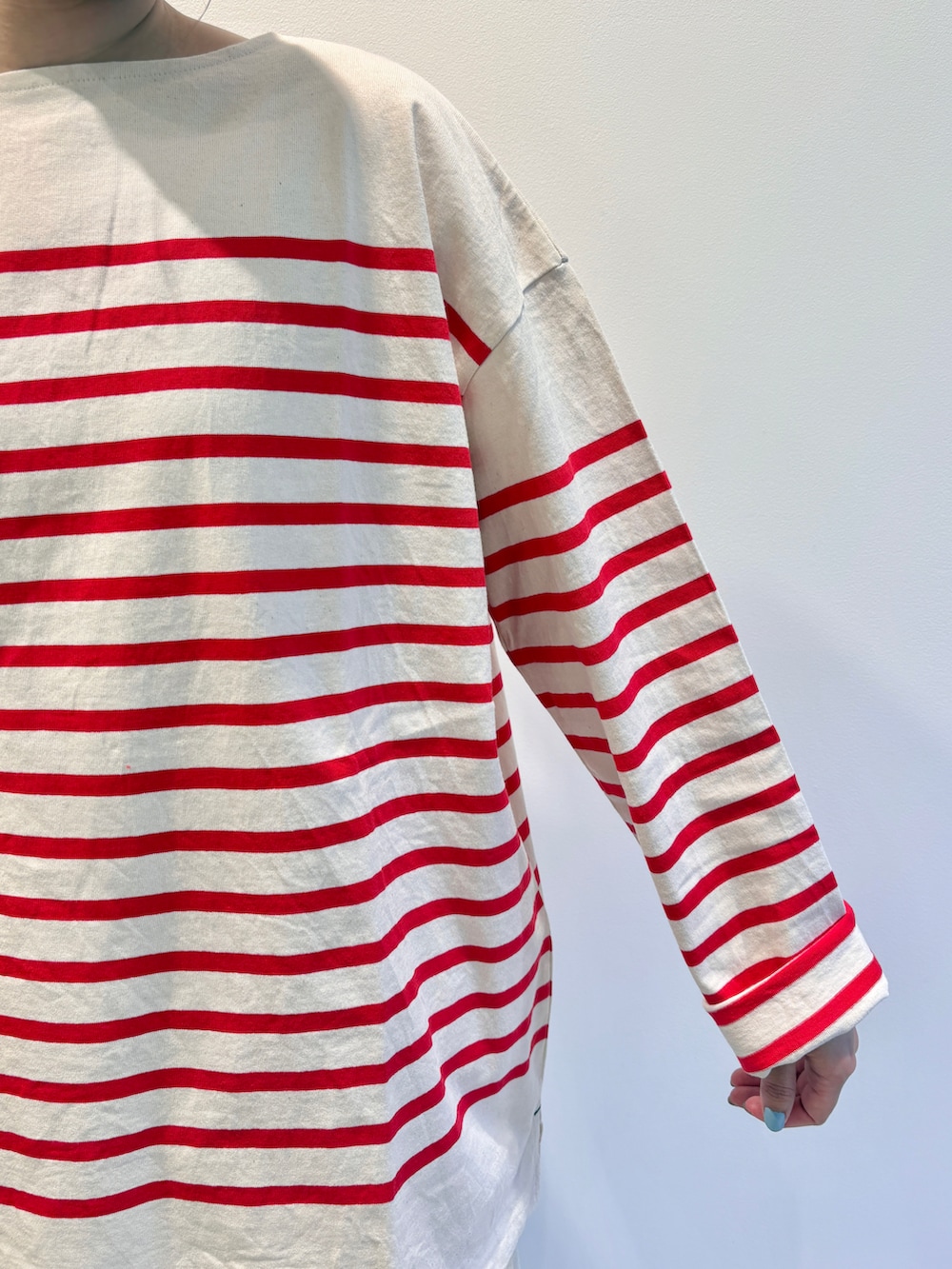 レッド系のTシャツ/カットソー、ホワイト系のスカート、グリーン系のキャップを着用したレディースの夏コーディネートの3枚目の写真