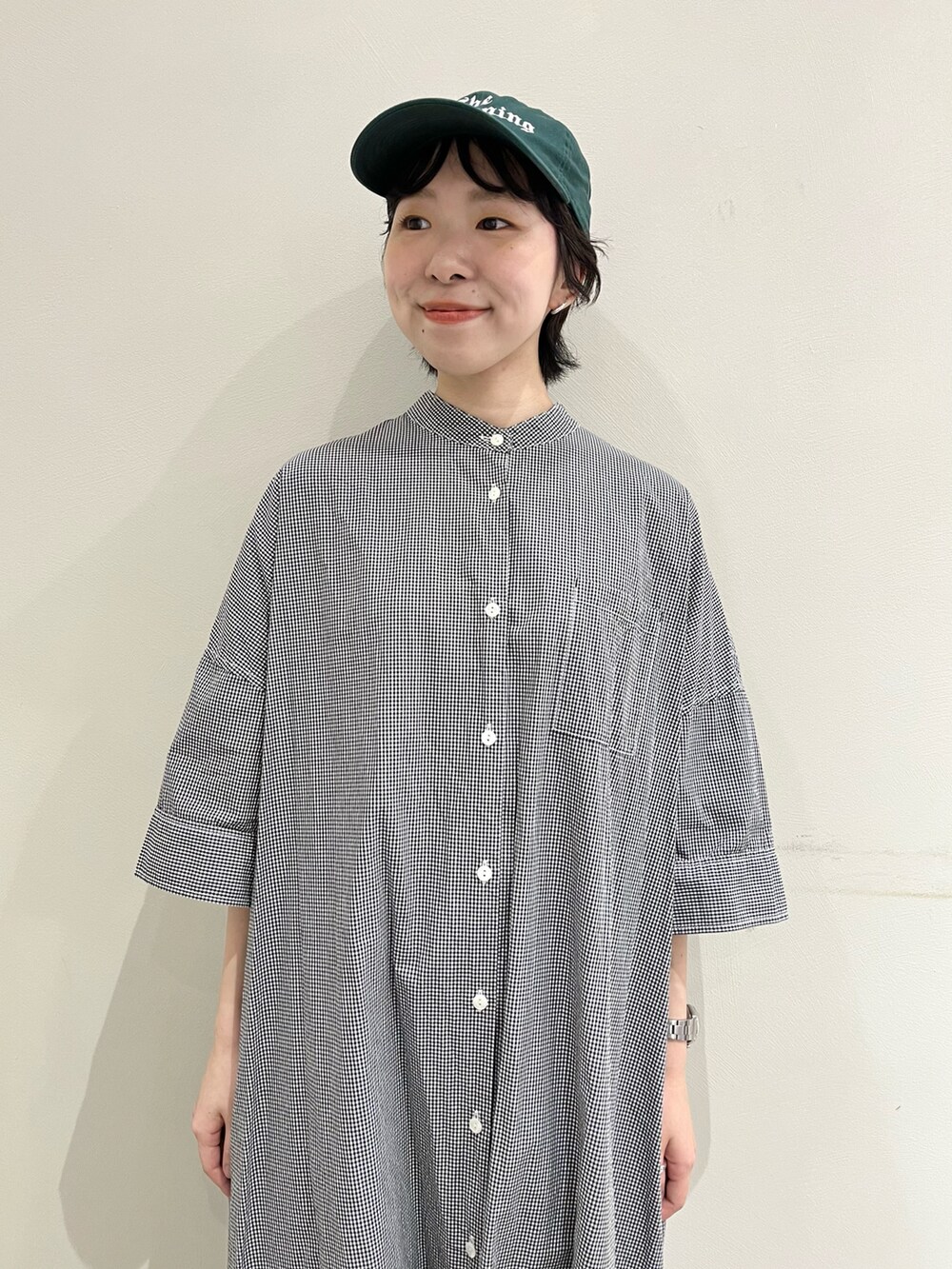 ブラック系のシャツワンピース、ブルー系のデニムパンツを着用したレディースの夏コーディネートの4枚目の写真