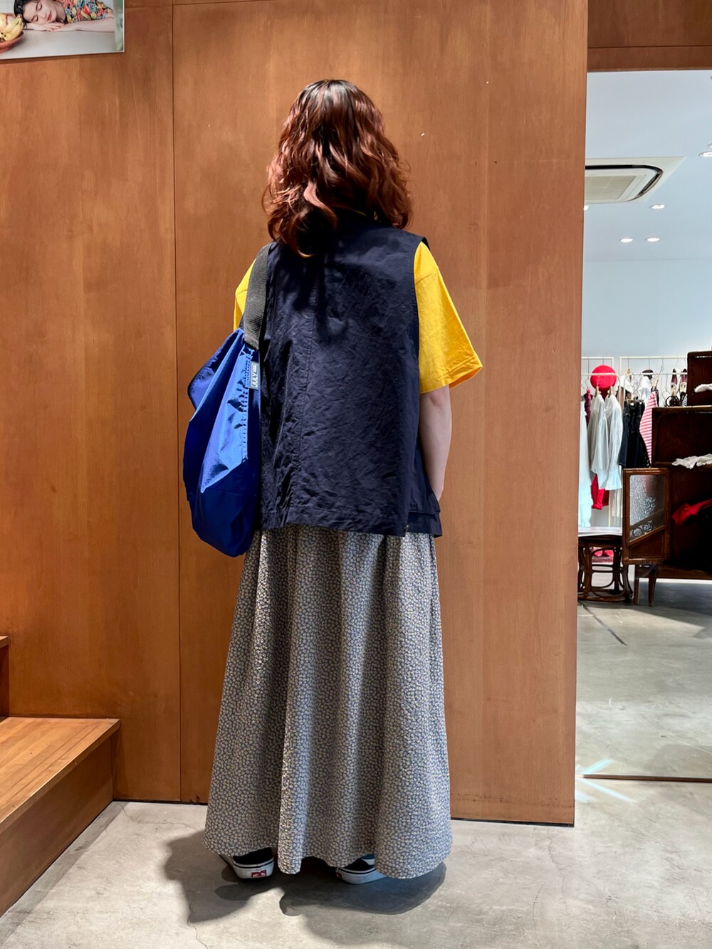 イエロー系のTシャツ/カットソー、ブルー系のベスト、イエロー系のスカートを着用したレディースの春コーディネートの2枚目の写真