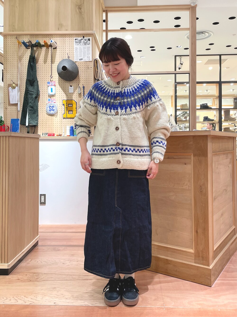 ホワイト系のカーディガン/ボレロ、グレー系のシャツ/ブラウス、ブルー系のデニムスカートを着用したレディースの秋コーディネートの2枚目の写真