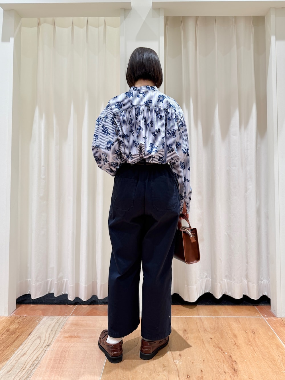 ブルー系のシャツ/ブラウス、ブルー系のチノパンツ、ブラウン系のショルダーバッグを着用したレディースの春コーディネートの2枚目の写真