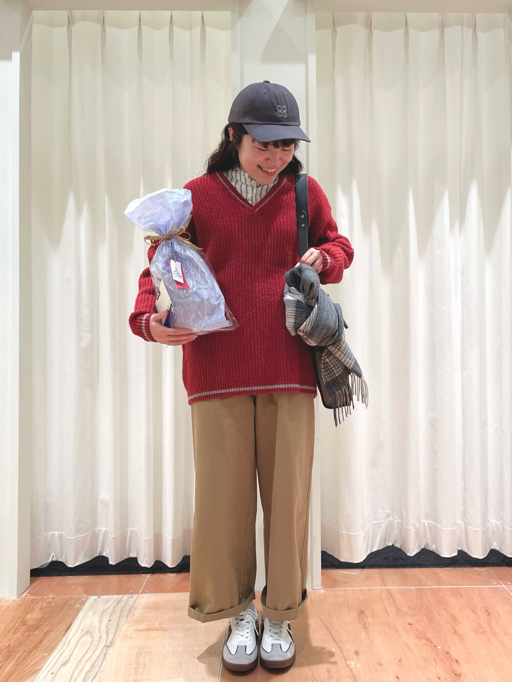 レッド系のニット/セーター、ベージュ系のチノパンツ、グリーン系のシャツ/ブラウスを着用したレディースの冬コーディネートの2枚目の写真