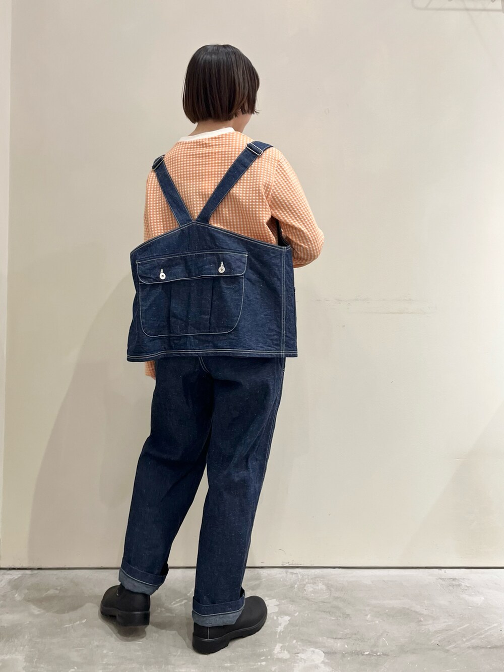 オレンジ系のTシャツ/カットソー、ブルー系のベスト、ブルー系のその他パンツを着用したレディースの冬コーディネートの3枚目の写真