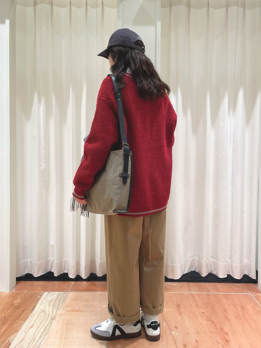 レッド系のニット/セーター、ベージュ系のチノパンツ、グリーン系のシャツ/ブラウスを着用したレディースの冬コーディネートの3枚目の写真