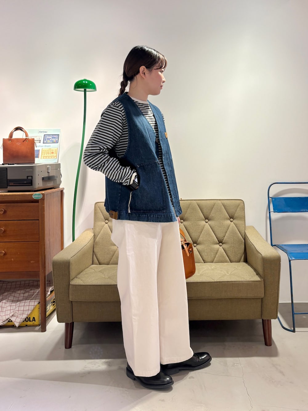 ブルー系のベスト、グリーン系のTシャツ/カットソー、ホワイト系のチノパンツを着用したレディースの冬コーディネートの2枚目の写真