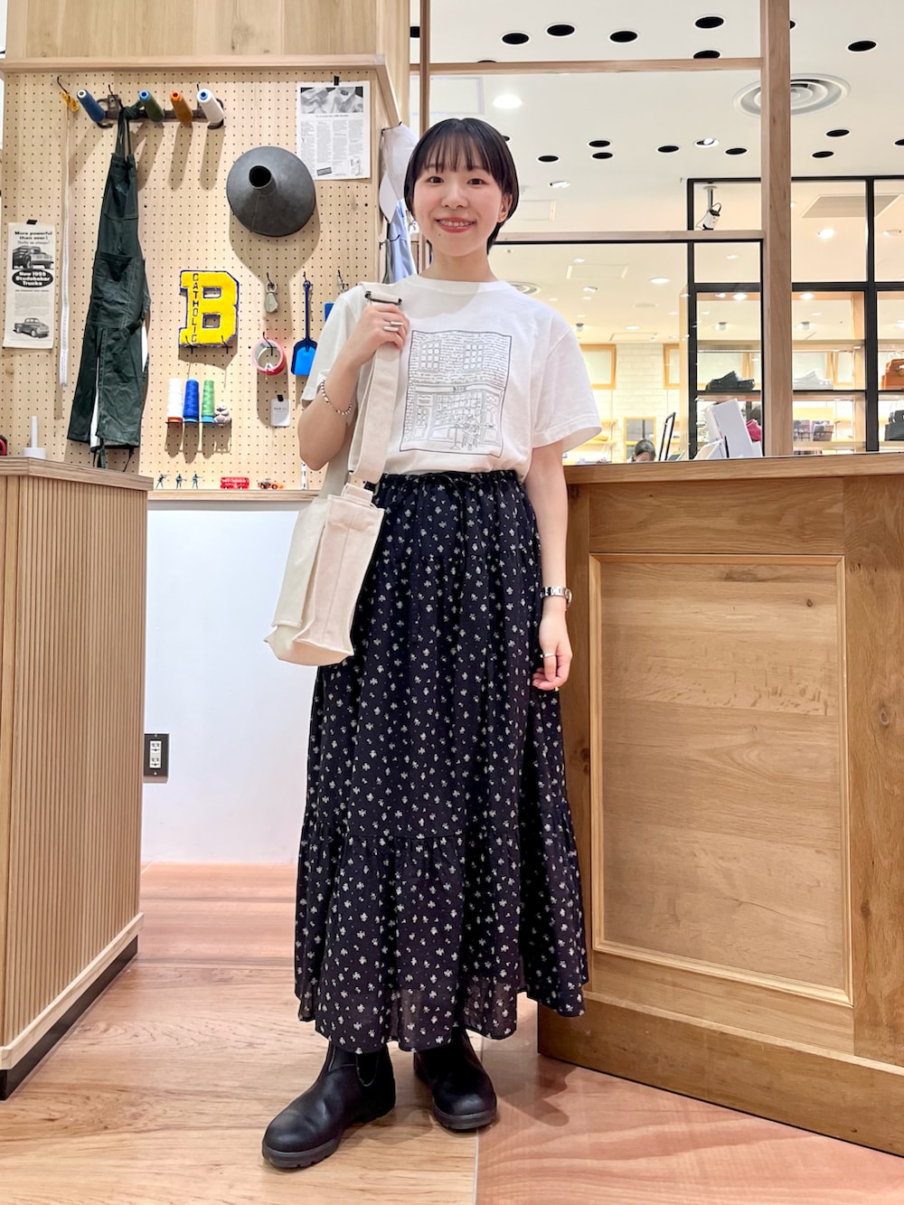 ホワイト系のTシャツ/カットソー、ホワイト系のショルダーバッグ、ブラック系のスカートを着用したレディースの夏コーディネートの2枚目の写真