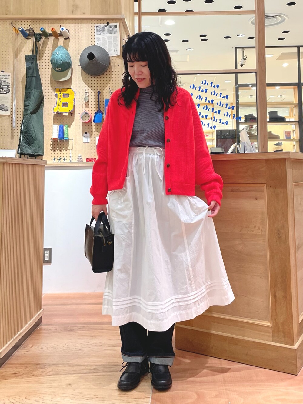 オレンジ系のカーディガン/ボレロ、ブルー系のTシャツ/カットソー、ホワイト系のスカートを着用したレディースの秋コーディネートの4枚目の写真