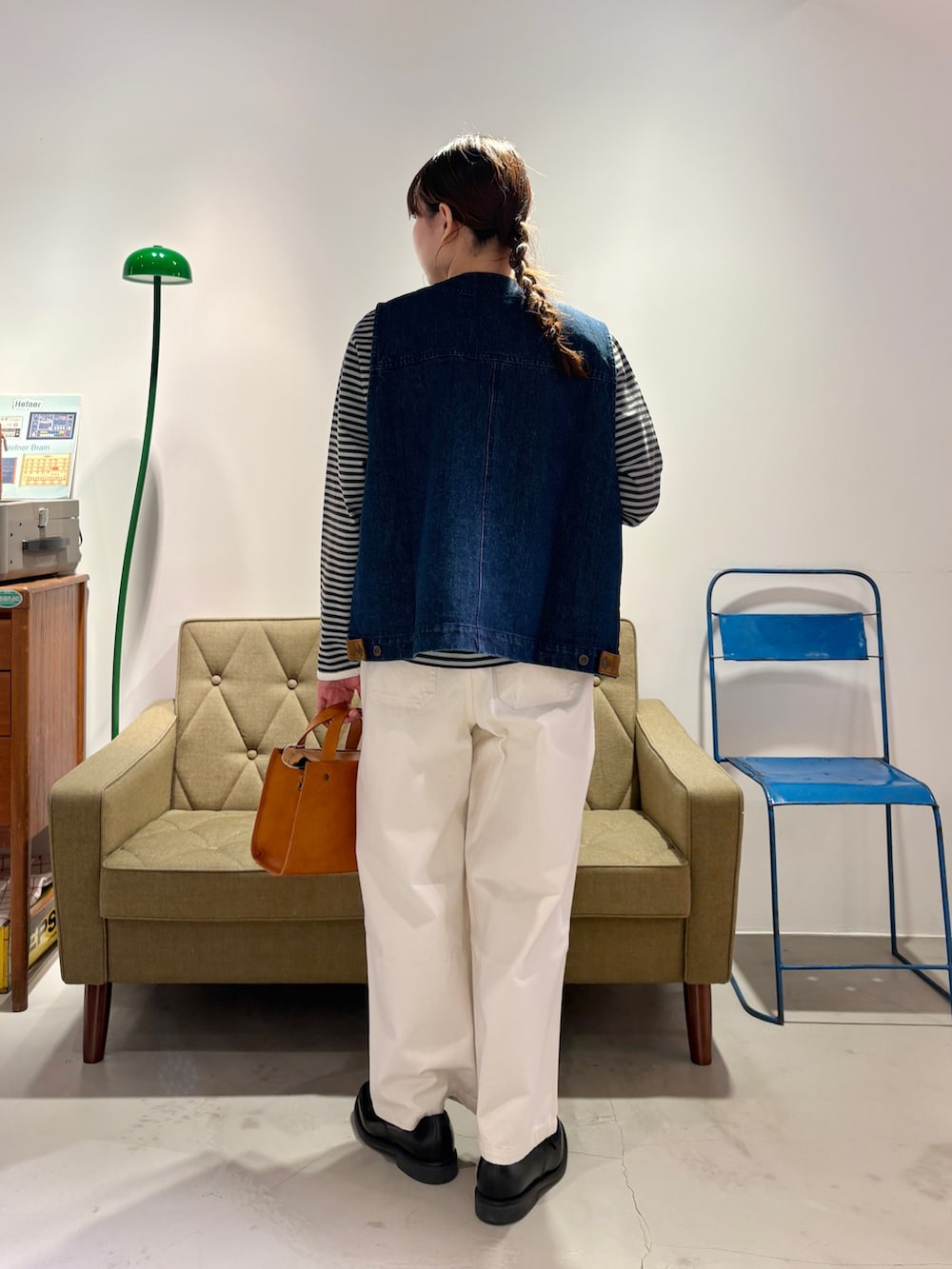 ブルー系のベスト、グリーン系のTシャツ/カットソー、ホワイト系のチノパンツを着用したレディースの冬コーディネートの3枚目の写真