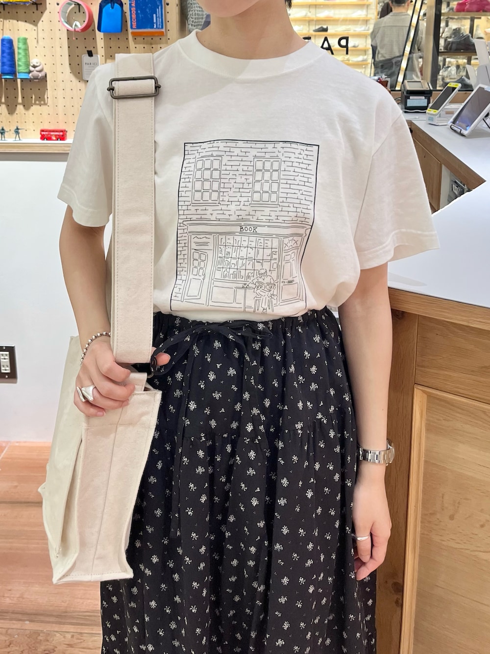 ホワイト系のTシャツ/カットソー、ホワイト系のショルダーバッグ、ブラック系のスカートを着用したレディースの夏コーディネートの4枚目の写真